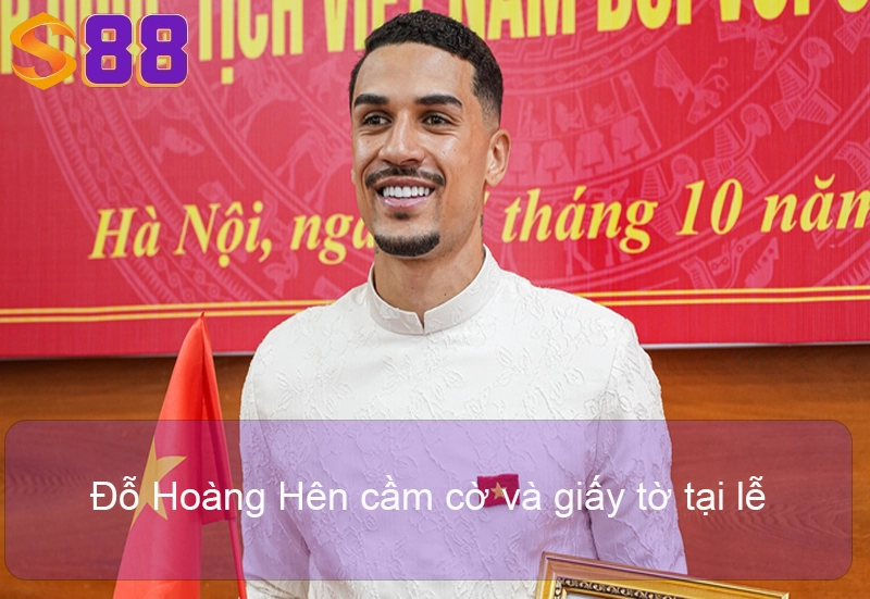 Hendrio Chính Thức Nhập Tịch Việt Nam - UPDATE 17/10/2025 Đỗ Hoàng Hên cầm cờ và giấy tờ tại lễ.